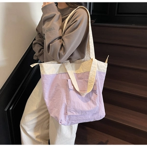 Detail of a lilac and cream large tote bag with a front flap pocket and zipper closure