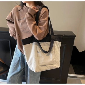Detail view of canvas tote bag featuring contrast colors and a large front flap pocket