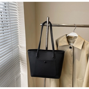 Detail der schwarzen Tote-Bag aus genarbtem Leder mit Druckknopftasche und schmalen Riemen