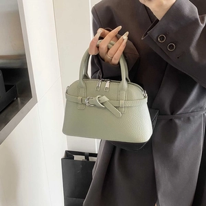 Detail of sage green crossbody bag showing pebble grain texture and metal zipper