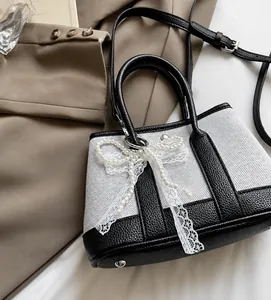 Detail of contrast tote bag featuring pearl bow, lace accents and lychee leather trim