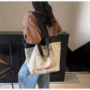 Canvas tote bag with large capacity featuring contrast stitching and front flap pocket detail