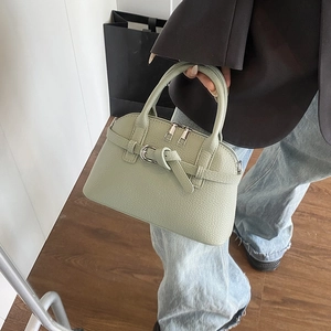 Close-up of light green shell bag with lychee grain leather texture and metal buckle