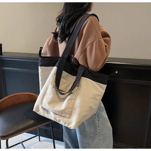 Detailed view of spacious canvas tote bag with contrast pocket on a shoulder-worn model