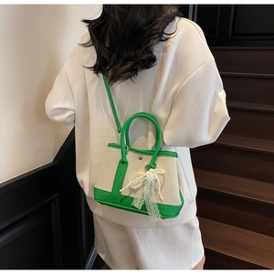 Detail of canvas bag with green leather trim and elegant pearl lace bow charm