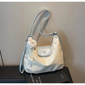 Détail du sac fourre-tout blanc cassé avec rabat bleu et pendentif boule de peluche blanche