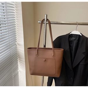 Detail einer braunen Shopper-Tasche mit Litschimuster und funktionaler Fronttasche