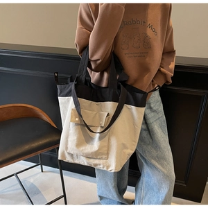 Close-up of contrast canvas tote bag with wide shoulder strap and metal buckle detail