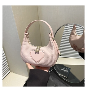 Close-up of pink heart-shaped handbag with woven texture and gold zipper detail