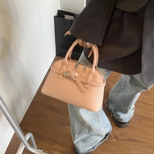 Detail of peach pebbled leather handbag featuring twin handles and buckle trim