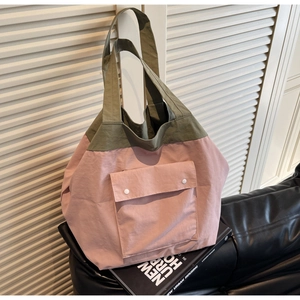 Detail of color-block tote bag featuring nylon texture and front pocket with snap buttons