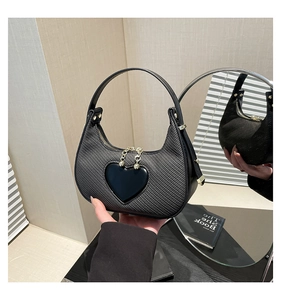 Close-up of black heart handbag featuring textured fabric and sleek metal chain detail