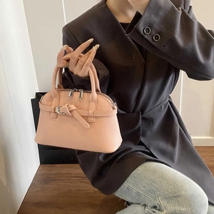 Close-up of pink leather handbag with lychee texture and silver double zippers