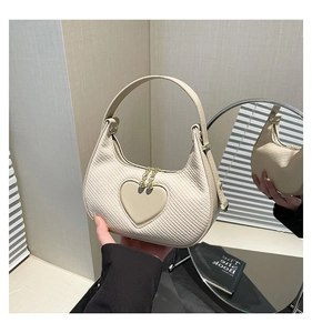 Detail of cream crescent bag with heart accent and woven leather texture details