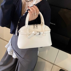 Detail of cream white shell handbag showing pebbled leather texture and knotted belt design
