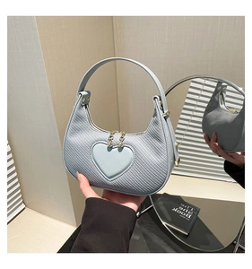 Detail of light blue crescent bag with heart patch and gold metal hardware
