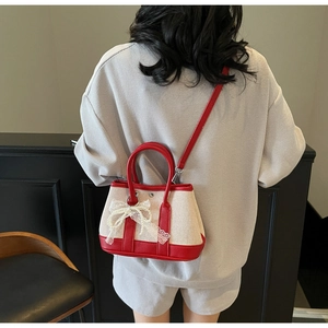 Detail view of mini red and white contrast bag with lace bow charm on model back