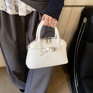 Detailed close-up of white lychee pattern handbag with silver zippers and bow buckle