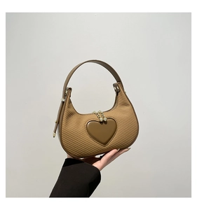 Detailansicht einer braunen Hobo-Tasche mit Herz-Patch und goldenem Kettenanhänger