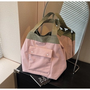 Detail of pink and olive green tote bag featuring a front flap pocket with snap buttons