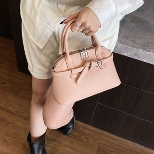 Detail of pink lychee leather handbag with a bow decoration and silver double zipper