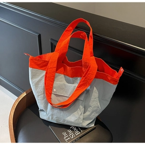 Detail of minimalist color-block tote bag in orange and blue nylon with snap pocket