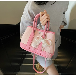 Close-up of pink contrast tote bag with pearl bow and lace details on stairs