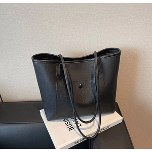 Detail einer schwarzen Tote-Bag aus genarbtem Leder mit praktischer Fronttasche