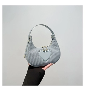 Nahaufnahme der hellblauen Herz-Handtasche mit Webstruktur und goldenen Metallbeschlägen