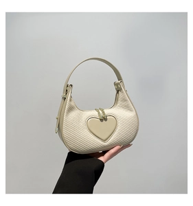 Nahaufnahme der beigen gewebten Handtasche mit herzförmigem Lederpatch und Goldbeschlägen