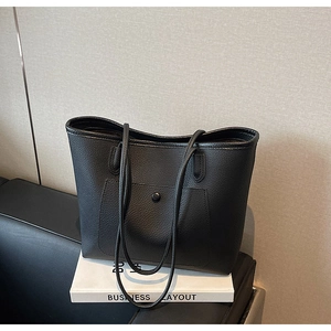Detail der schwarzen Shopper-Tasche mit Kieseltextur und vorderer Druckknopftasche