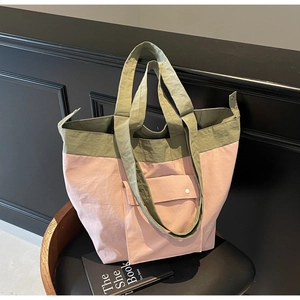 Detail of color-block canvas tote bag with pink and olive green panels on a black chair