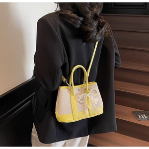 Crossbody view of canvas patchwork bag with yellow leather and pearl bow detail