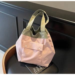 Detail of a pink and olive green contrast tote bag with snap-button front pocket texture