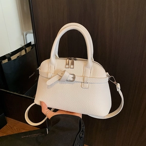 Detail of white lychee pattern shell bag with silver buckle and leather strap texture