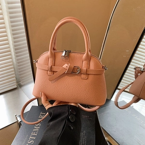 Detail view of the peach-colored lychee textured leather crossbody bag with top handles