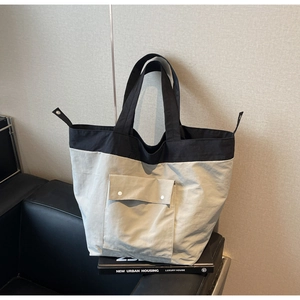 Detail of the color-block tote bag featuring a front flap pocket and durable nylon texture