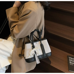 Detail of canvas tote bag with black leather trim and lace pearl bow charm detail