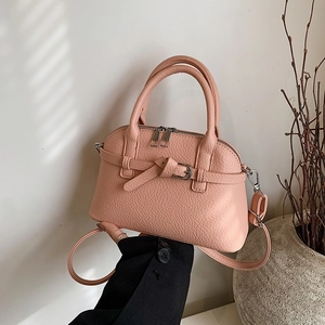 Detail of pink lychee leather shell bag featuring double handles and silver buckles
