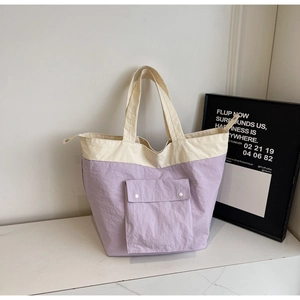 Detail of lavender and cream canvas tote bag showing the front flap pocket with snap buttons