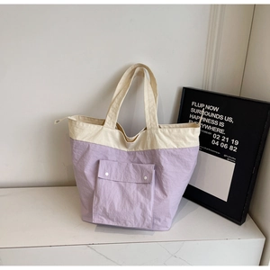 Detail of light purple nylon tote bag featuring front pocket with dual silver snaps