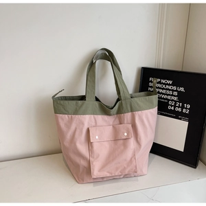 Close-up of olive green and pink tote bag with buttoned front pocket on marble surface