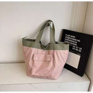 Detail of multi-pocket tote bag with pink canvas and olive green trim in close-up view