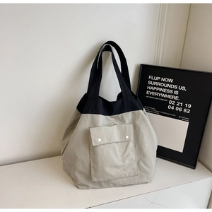 Detail of grey and black canvas tote bag showing the front pocket with silver snap buttons