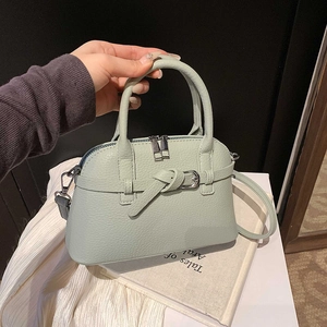 Detail of mint green lychee pattern leather handbag with stylish belt buckle and silver zipper