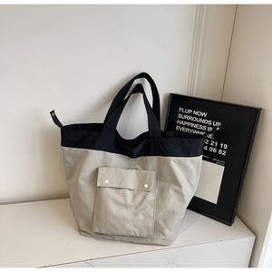 Detail of minimalist gray and black tote bag with metal buttons on front pocket