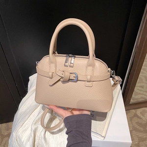 Close-up of beige lychee grain leather handbag with decorative knot and dual zipper