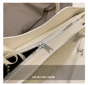 Close-up of premium metal zipper and woven leather texture on cream-colored handbag
