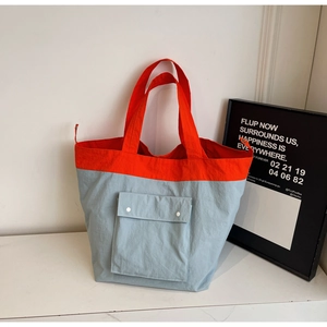 Detail of a large two-tone tote bag in orange and light blue with snap pocket