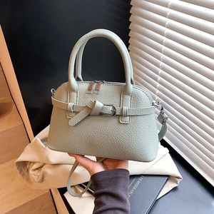 Detail shot of mint green pebble leather handbag with buckle strap and silver zipper
